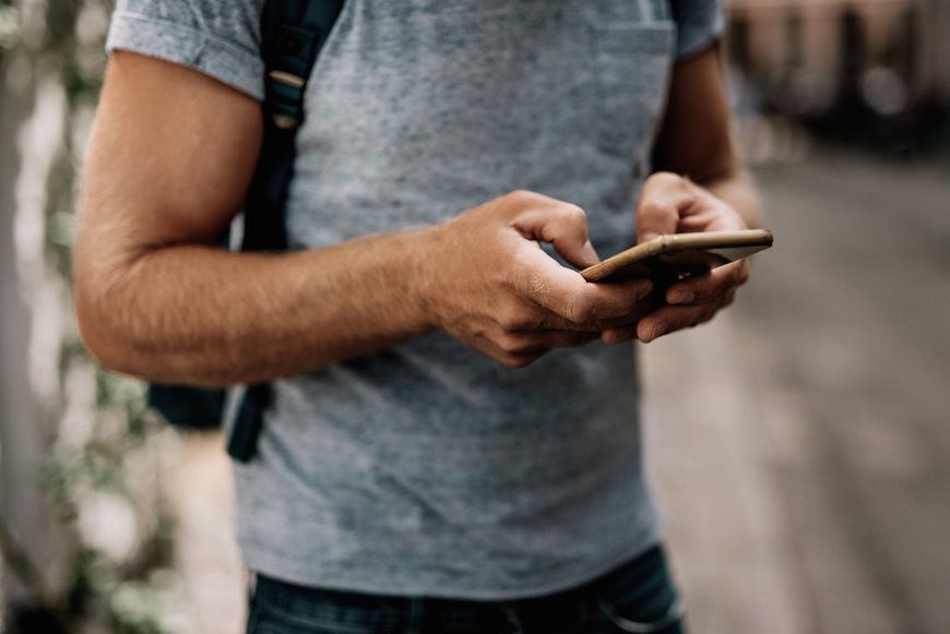 Mand i t-shirt holder mobiltelefon i hænderne