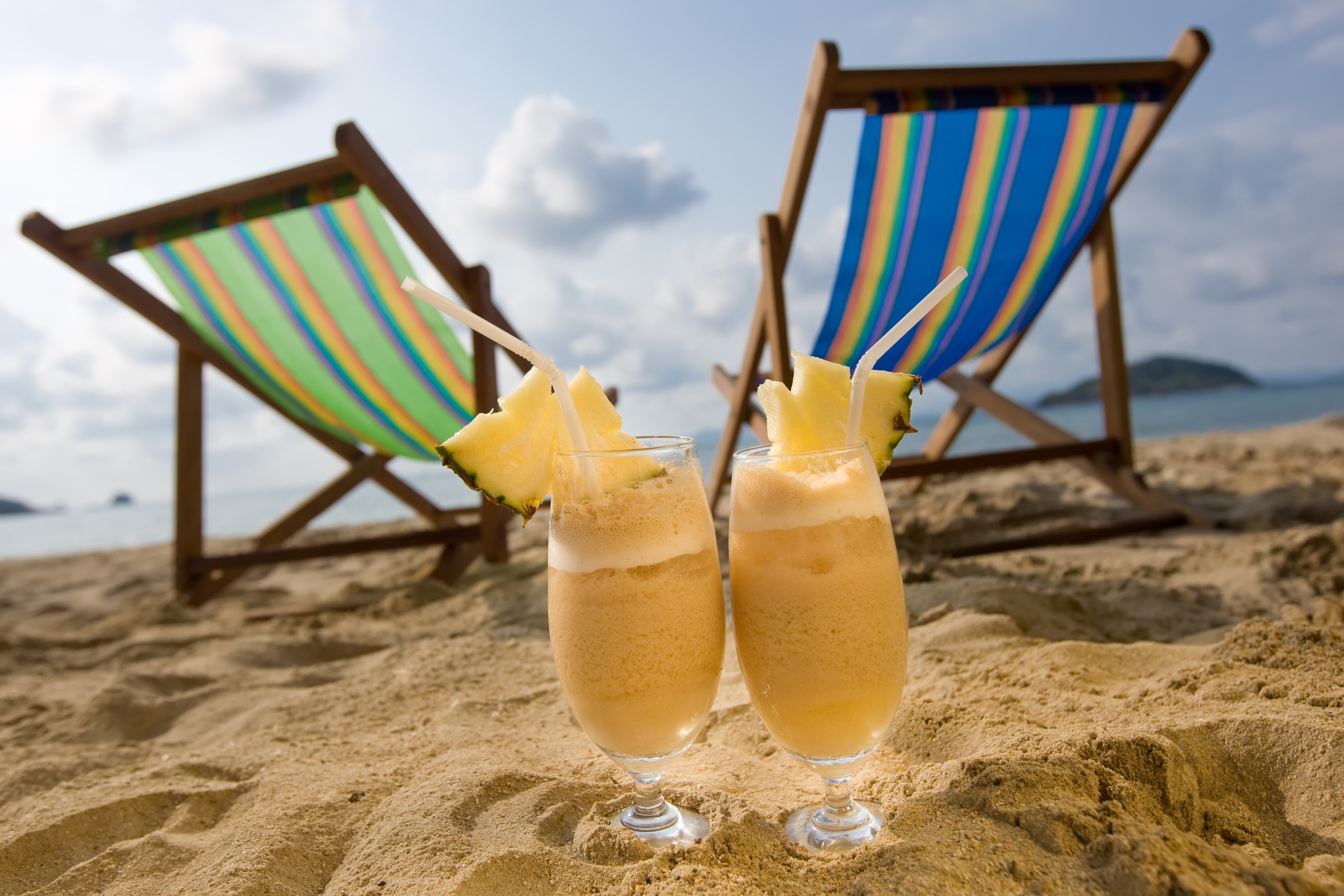To strandestole står på strand. Foran dem står to drinks