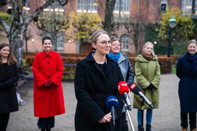 Lea Wemelin holder pressemøde udendørs. I baggrunden står de politiske forhandlere, som har været med til at indgå aftalen