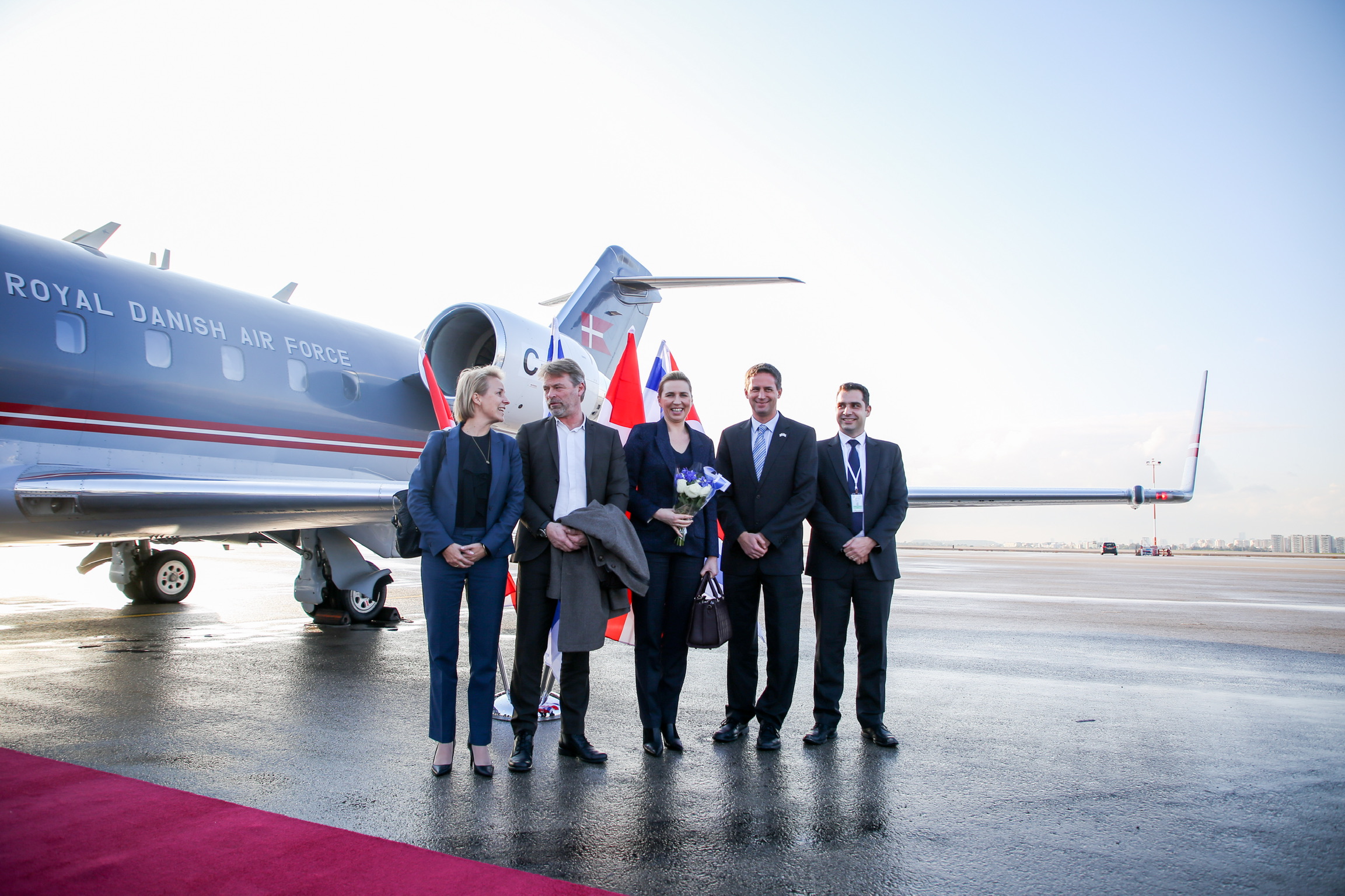 Statsminister Mette Frederiksen og hendes følge foran flyet på vej hjem til Danmark
